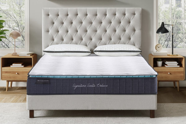 Mattress on a bed in a bedroom setting with wooden nightstands and a tufted headboard.